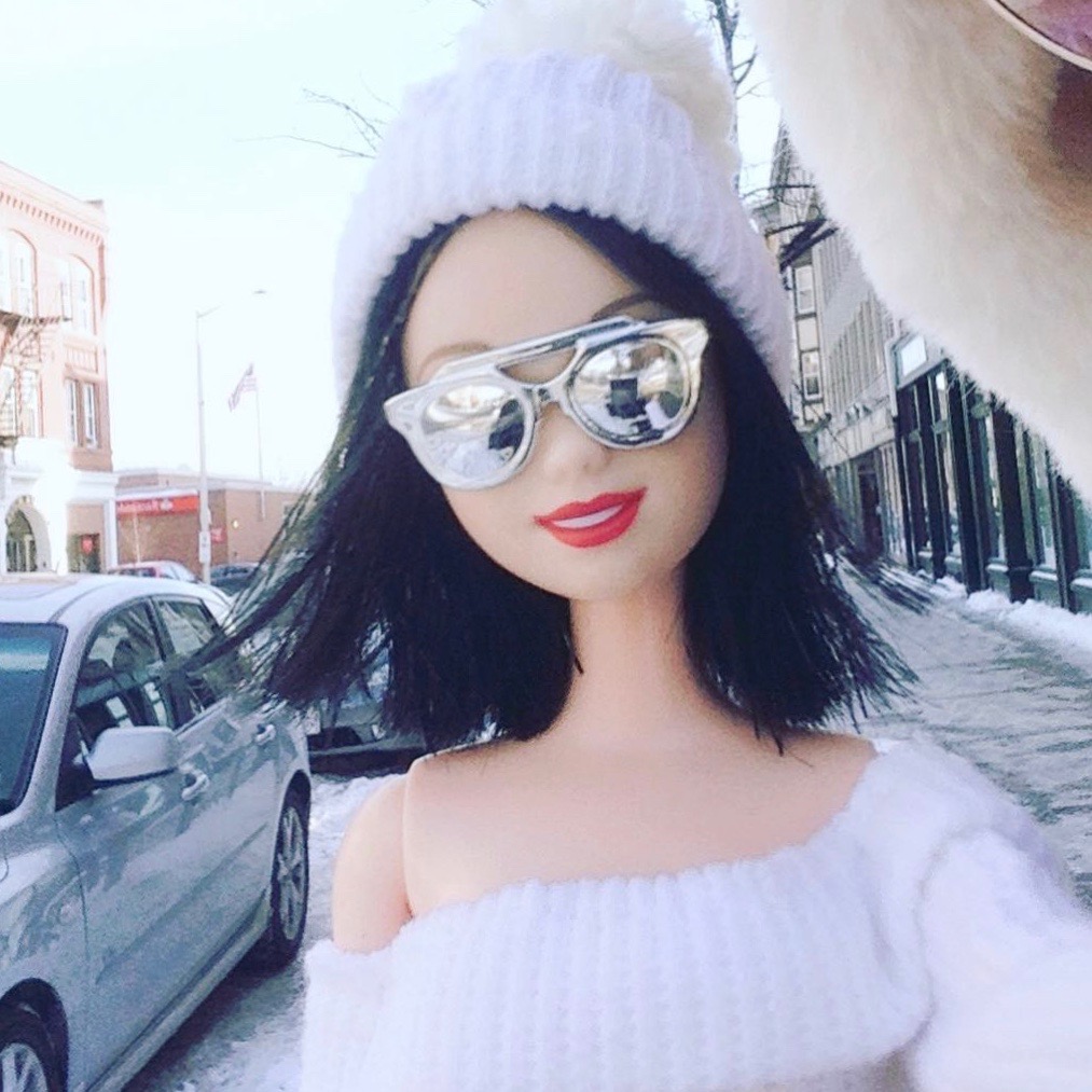 Doll wearing hat taking selfie